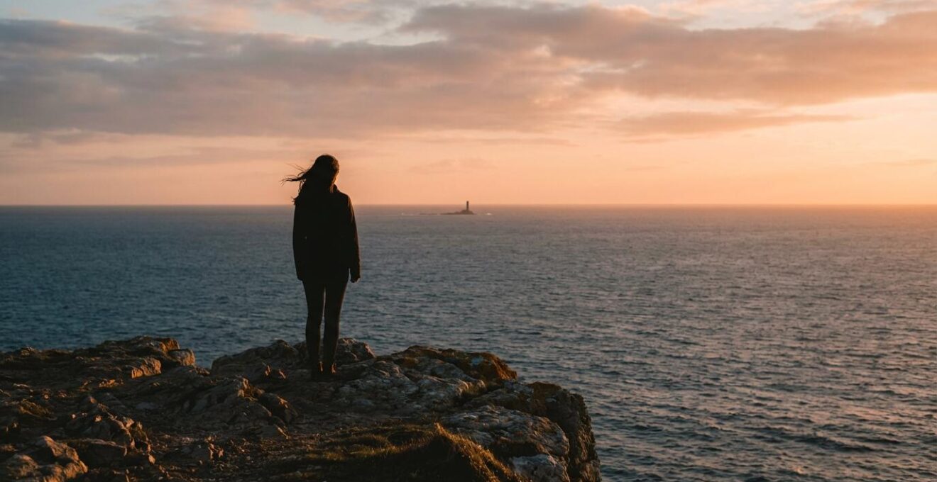 Personne seule contemplant un paysage naturel apaisant depuis une falaise au coucher du soleil