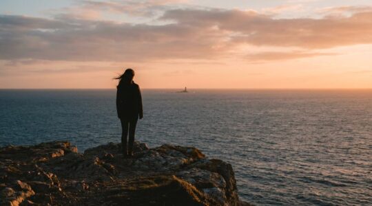 Personne seule contemplant un paysage naturel apaisant depuis une falaise au coucher du soleil